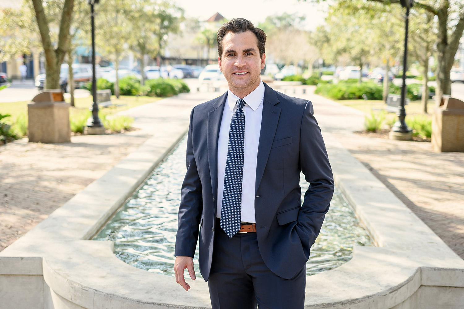 Portrait of Nader Jarun in a suit by water feature